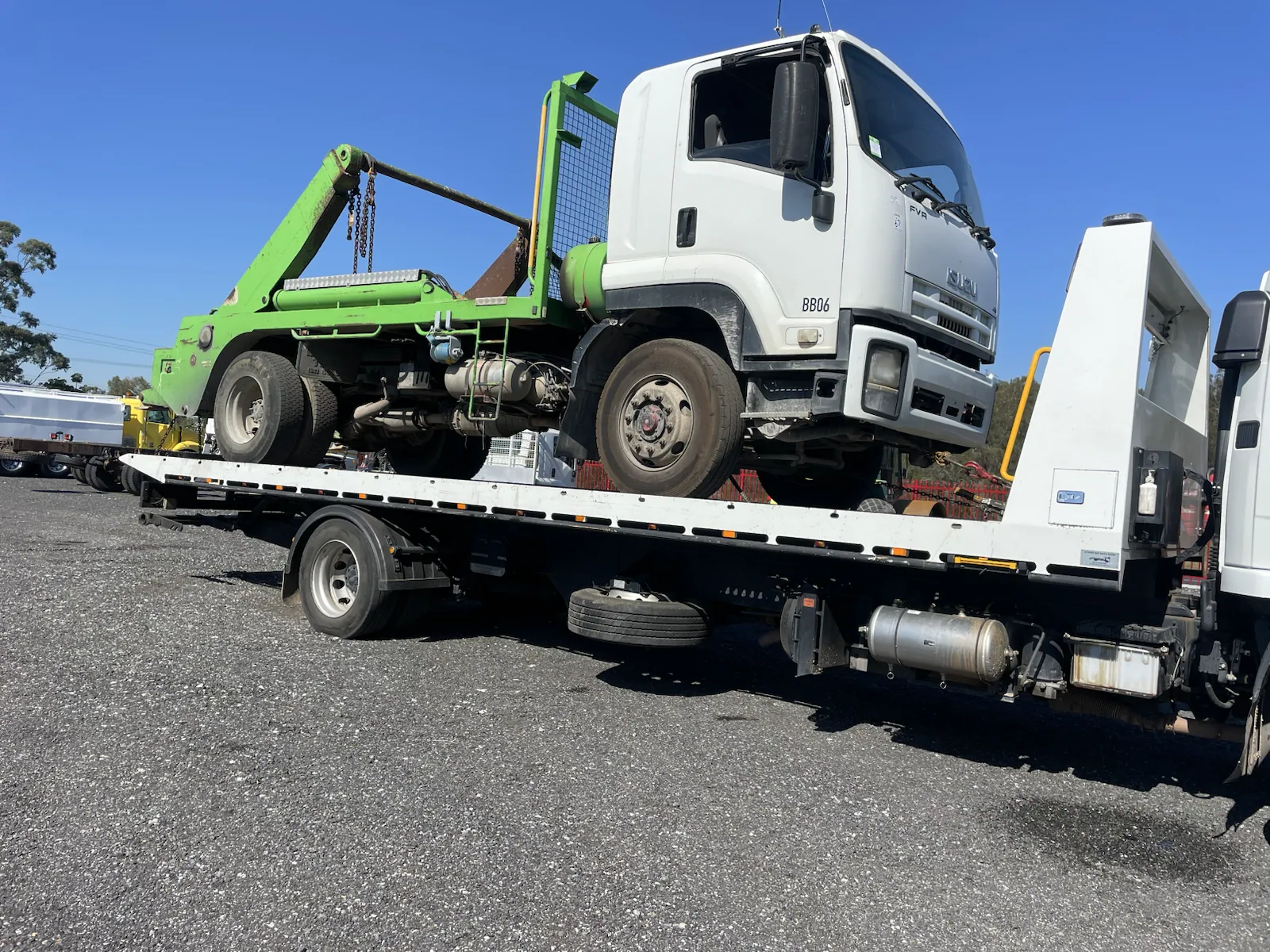 Green truck loaded on a tow truck for removal