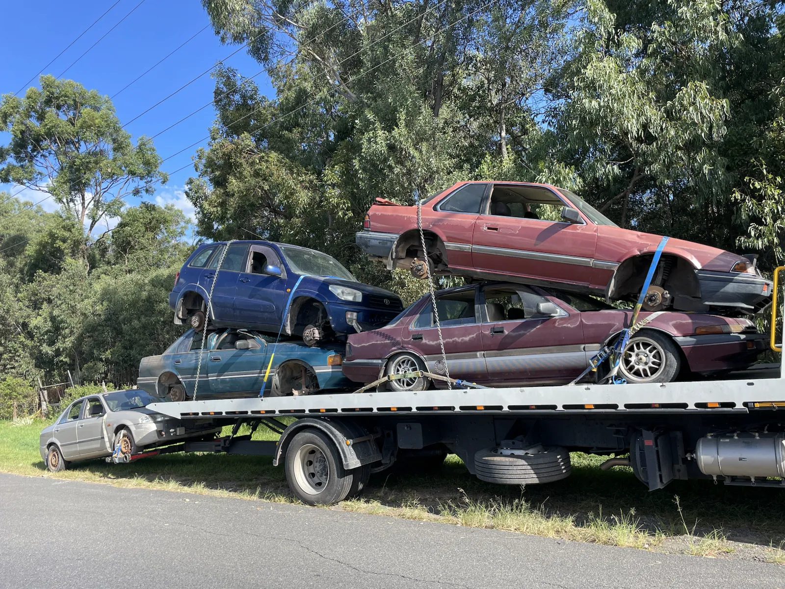 Several old vehicles stacked on a tow truck in Queensland