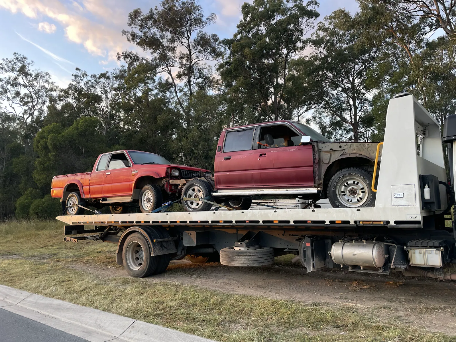 Two red utes loaded for vehicle removal in Queensland